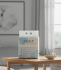 family pack of Enrich facial tissue on a wooden table in a family room with a painting and window in the background